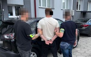 Zatrzymany mężczyzna prowadzony przez policjantów.