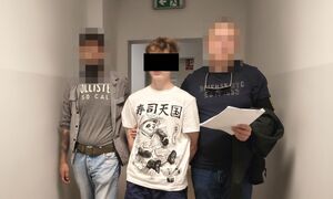 Zatrzymany mężczyzna prowadzony przez policjantów.