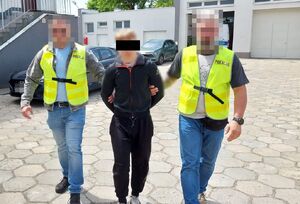 Zatrzymany mężczyzna prowadzony przez policjantów.