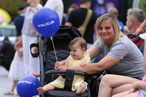 Kobieta z małym dzieckiem trzyma balon z napisem policja.