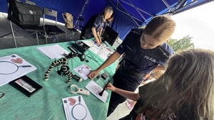 Policjantka pokazuje jak zabezpieczać ślady linii papilarnych.
