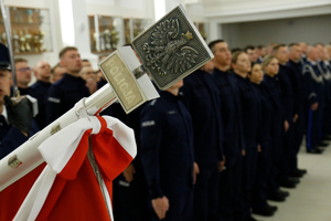 W pierwszym planie grot sztandaru na którym widać godło Polski. W tle młodzi funkcjonariusze policji.