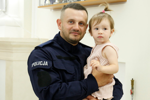 Policjant trzyma na rękach córeczkę.