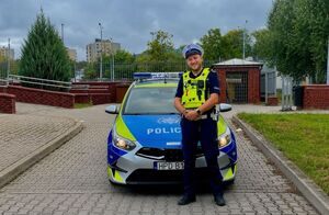 umundurowany policjant stoi przy radiowozie