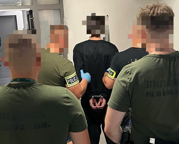 policjanci ze strażą graniczną pilnują zatrzymanego