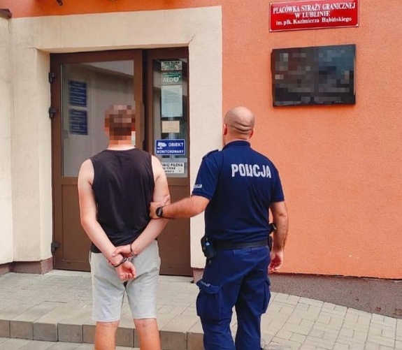 policjant wprowadza zatrzymanego do placówki straży granicznej