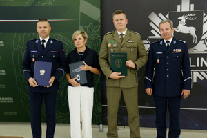 Komendant Powiatowy Policji w Opolu Lubelskim nadkomisarz Jarosław Kurczak, Dyrektor Liceum Ogólnokształcącego imienia Adama Mickiewicza w Opolu Lubelskim Pani Monika Ptasińska-Romanowska, Komendant Powiatowy Policji w Kraśniku podinspektor Przemysław Wronka, Dyrektor Zespołu Szkół numer 3 w Kraśniku, Zastępca Komendanta Nadbużańskiego Oddziału Straży Granicznej płk SG Jan Szynal i I zastępca Komendanta Wojewódzkiego Policji w Lublinie inspektor Andrzej Mioduna stoją obok siebie trzymając podpisane porozumienie