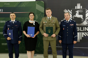 Komendant Powiatowy Policji w Kraśniku podinspektor Przemysław Wronka, Dyrektor Zespołu Szkół numer 3 w Kraśniku, Zastępca Komendanta Nadbużańskiego Oddziału Straży Granicznej płk SG Jan Szynal i I zastępca Komendanta Wojewódzkiego Policji w Lublinie inspektor Andrzej Mioduna stoją obok siebie trzymając podpisane porozumienie