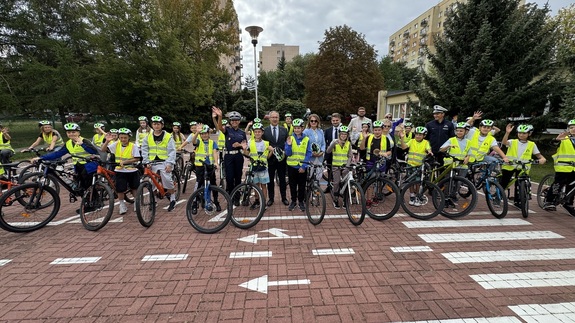Grupowe zdjęcie dzieci w kaskach ochronnych z policjantami i Wicewojewodą.
