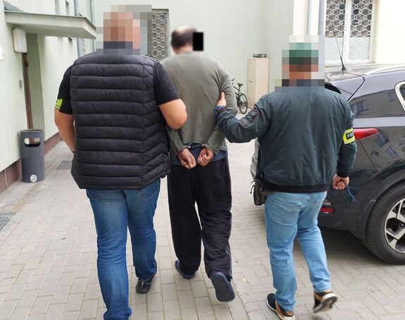 policjanci prowadzą zatrzymanego