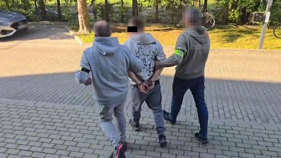 Policjanci prowadzą zatrzymanego mężczyznę.
