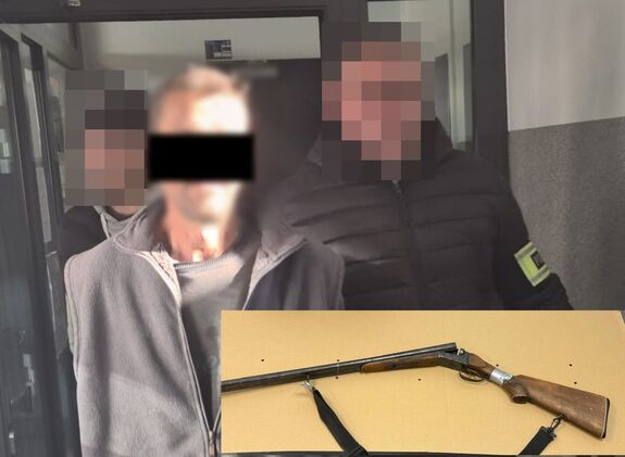 Policjanci prowadzą zatrzymanego mężczyznę. W dolnej części zdjęcia zabezpieczona broń myśliwska.