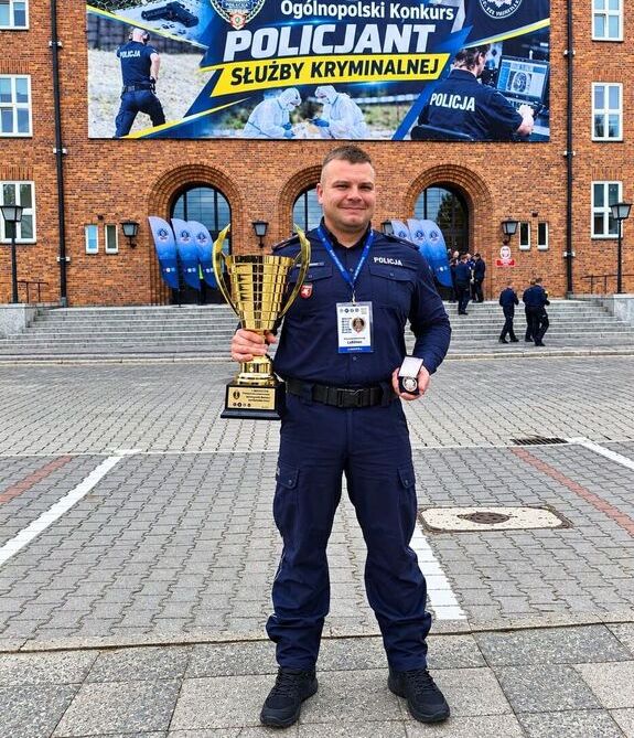 Policjant z pucharem na tle budynku